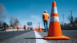 © Bargais - Traffic cones on an empty road with a construction worker in the background.