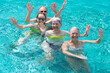 © luciano - Cheerful group of four relaxed friends having fun in outdoor swimming pool under the sun. Vacation and freedom, summer vibes concept