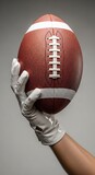 American football in hand with white glove against gray background