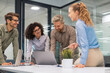 © ty - Happy four business people executive team working at laptop having discussion at office meeting showing financial project