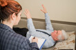 © Михаил Решетников - An elderly man lies on a couch and holds his hands hanging during an appointment with a hypnotherapist. An elderly male patient in an individual consultation with a female psychologist