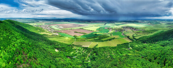 Poster - Storm rainy clouds above a village and green mountain and field landscape - panorama of Slovakia