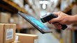 © MichaelMob - A worker scans packages with a barcode scanner and tablet in a warehouse for inventory management.