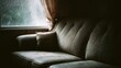 © VK Studio - A moody, textured sofa bathed in muted light from a rainy window creates a cozy, introspective scene.