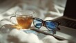 © VK Studio - Sunglasses and a glass mug of tea rest on a laptop, basking in the cozy warmth of a sunlit blanket scene designed for tranquility.