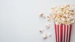 © Mariquita vector - Freshly popped popcorn spilling out of a red and white striped container on a plain background with a sense of snack time delight