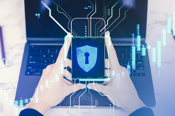 Fototapete - Person holding smartphone displaying digital lock symbol, representing cybersecurity and data protection, with tech interface overlay on laptop.