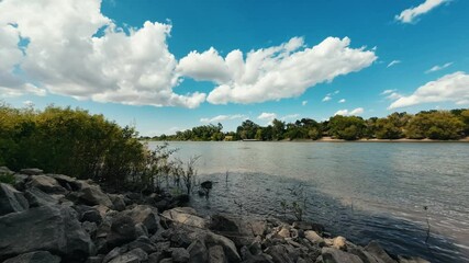 Wall Mural - Time-lapse of the white clouds rolling in the clear blue sky over a flowing river on a sunny day