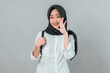 © Saddha Visual - Smiling young Muslim student wearing a black hijab and white shirt with a backpack, making a cheerful hand gesture, ready to go back to school with excitement.