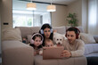 © asier - Family enjoying digital tablet on sofa with headphones and dog