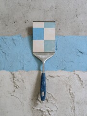 Poster - Tile Adhesive Spatula Rests on Concrete Surface Alongside Color Pattern Samples for a Home Renovation Project