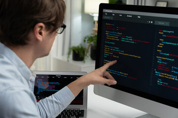 IT developer selecting by point on coding online software development information on pc comparing with laptop screen of new code program's update version firmware overall system project. Pecuniary.