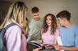 © Miljan Živković - group of students study together from notebook on the school hallway