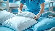© Hajrah - Nurse preparing hospital bed with white pillow, wearing gloves and blue scrubs