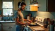 © WIWIK - A young man is cooking breakfast in a small kitchen while listening to music from headphones,eating,lifestyle