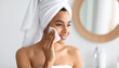 © Hyejin Kang - A woman wearing a white towel on her head and gently massaging her face with a cleansing tissue.