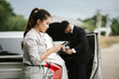 © Witoon - Man and woman standing by damaged car after accident, examining vehicle and filing insurance claim with agent for roadside assistance and repair.