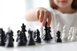 © MUdaylah - Close-up of a little girl's hand playing chess on a table, with a white background and a blurred background.