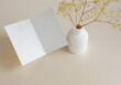 © irenastar - Greeting Card mockup, folded empty white blank,  dry flowers in a vase, on beige background. copy space. Minimalist aesthetic composition
