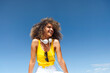 © Westend61 - Cheerful young woman with curly hair looking away sitting under blue sky on sunny day