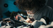 © ABCreative - A young boy wearing safety goggles carefully solders wires at his desk, immersed in learning electronics repair. His focus and curiosity reveal an early passion for engineering.