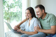 © Antonioguillem - Happy couple using a laptop together in a house interior