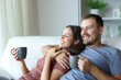 © Antonioguillem - Happy couple drinking tea looking away in a house interior