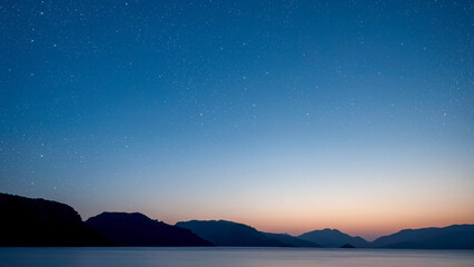 Wall Mural - a a movement of stars in the night sky with the view of mountains..