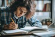 © Anna - Student studying at desk writing lecture notes in casual home setting