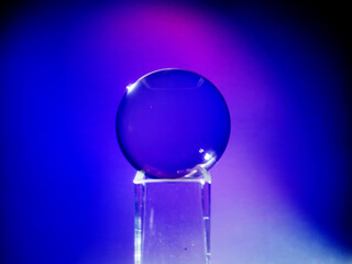 Wall Mural - a clear glass ball is sitting on a pedestal. colorful background. abstract graphic background. light