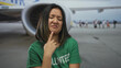 © Krakenimages.com - Young woman volunteer makes a disgusted face at an airport terminal with a plane in the background outdoors, conveying travel-related emotion.