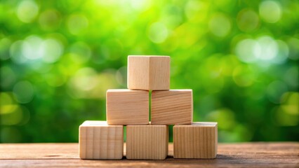 Poster - Wooden Blocks Stacked in a Pyramid on a Wooden Surface with a Blurred Green Background