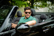 © gzorgz - A middle-aged man sitting in a convertible car and driving. Handsome male wearing casual clothes and sunglasses.