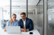 © Stock 4 You - Two partners, team of professional business people working, discussing work sitting at desk. Mature focused senior mentor leader man showing young woman manager project on laptop in office. Copy space
