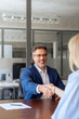 © Stock 4 You - Mature Latino bank worker man shaking hand with client, recruit female employee or business partner after signing a contract. Group of people satisfied with results of team work together. Vertical