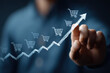 © Саша Федюк - Someone is sketching a rising graph with shopping cart icons, representing the surge in online sales and e-commerce growth, reflecting shifts in market trends and consumer behavior