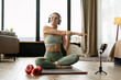 © Maria Vitkovska - Fitness trainer streaming online workout from home with smartphone