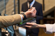 © pressmaster - Close-up of a contactless payment transaction at a checkout counter, showing hands and payment device, indicating secure and convenient transaction technology