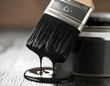 © Deva - Black Paint Brush Dripping: Close-up shot of a paint brush dripping black paint, beside a paint tin, evoking a sense of artistic creation and transformation.