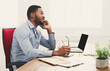 © Prostock-studio - Satisfying call. Young black businessman talking on mobile phone and working on laptop in modern white office, copy space