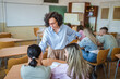 © Miljan Živković - Female teacher help high school students do exercises in classroom