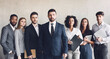 © Prostock-studio - Millennial business colleagues headed with boss, posing to camera over grey wall in office