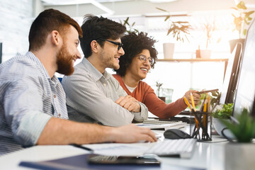 great job. three men enjoying good coding job on computer at modern office, empty space