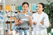 © JackF - Attentive young girl buyer choosing medical ointment and professional asian female parmacist helping in small pharmacy