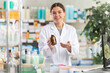 © JackF - Female pharmacist standing near counter in pharmacy and offering medicated throat syrup