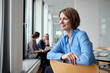 © Westend61 - Businesswoman in blue shirt smiling and looking out the window during a meeting in a modern office