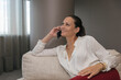 © Westend61 - Smiling mature female professional talking on mobile phone sitting on sofa looking away