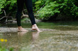 © Westend61 - Bare feet stepping into a stream in a green forest promoting holistic health and mental well-being