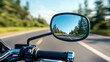 © JoxyAimages - The image captures the exhilarating view from a motorcycle mirror, reflecting a clear road ahead flanked by tall trees, symbolizing freedom, adventure, and the spirit of exploration.