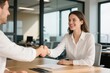 © Zhangxiao - A man and a woman in business attire shaking hands across a wooden table in a modern office setting